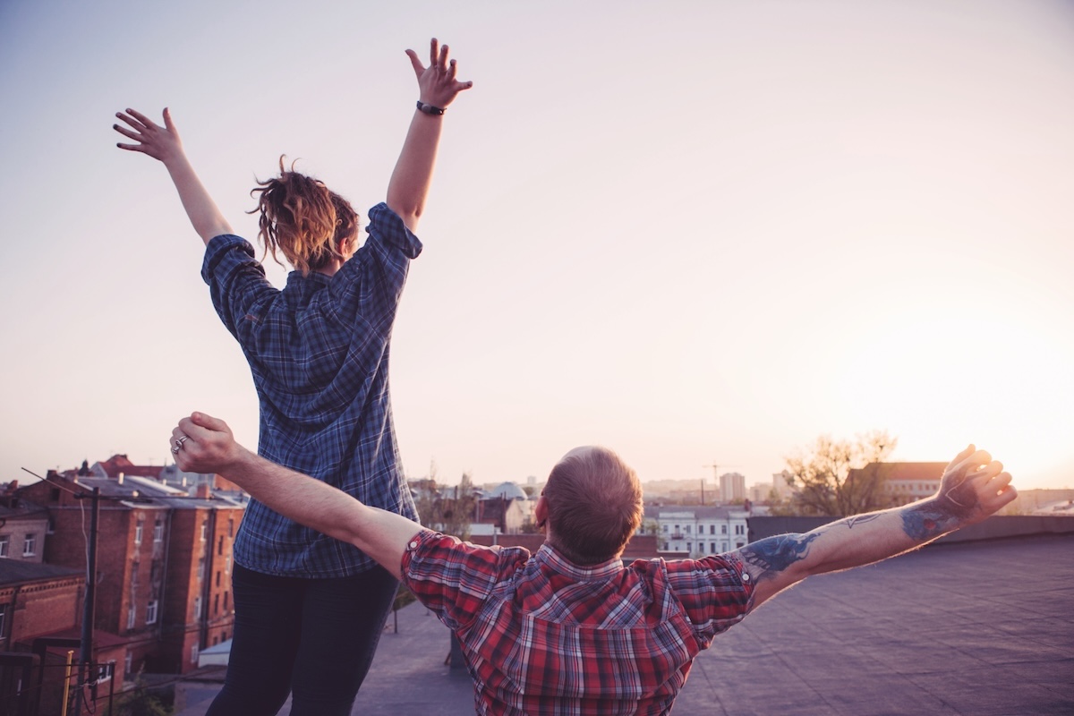 Zwei Freunde strecken die Arme in den Himmel bei Sonnenuntergang