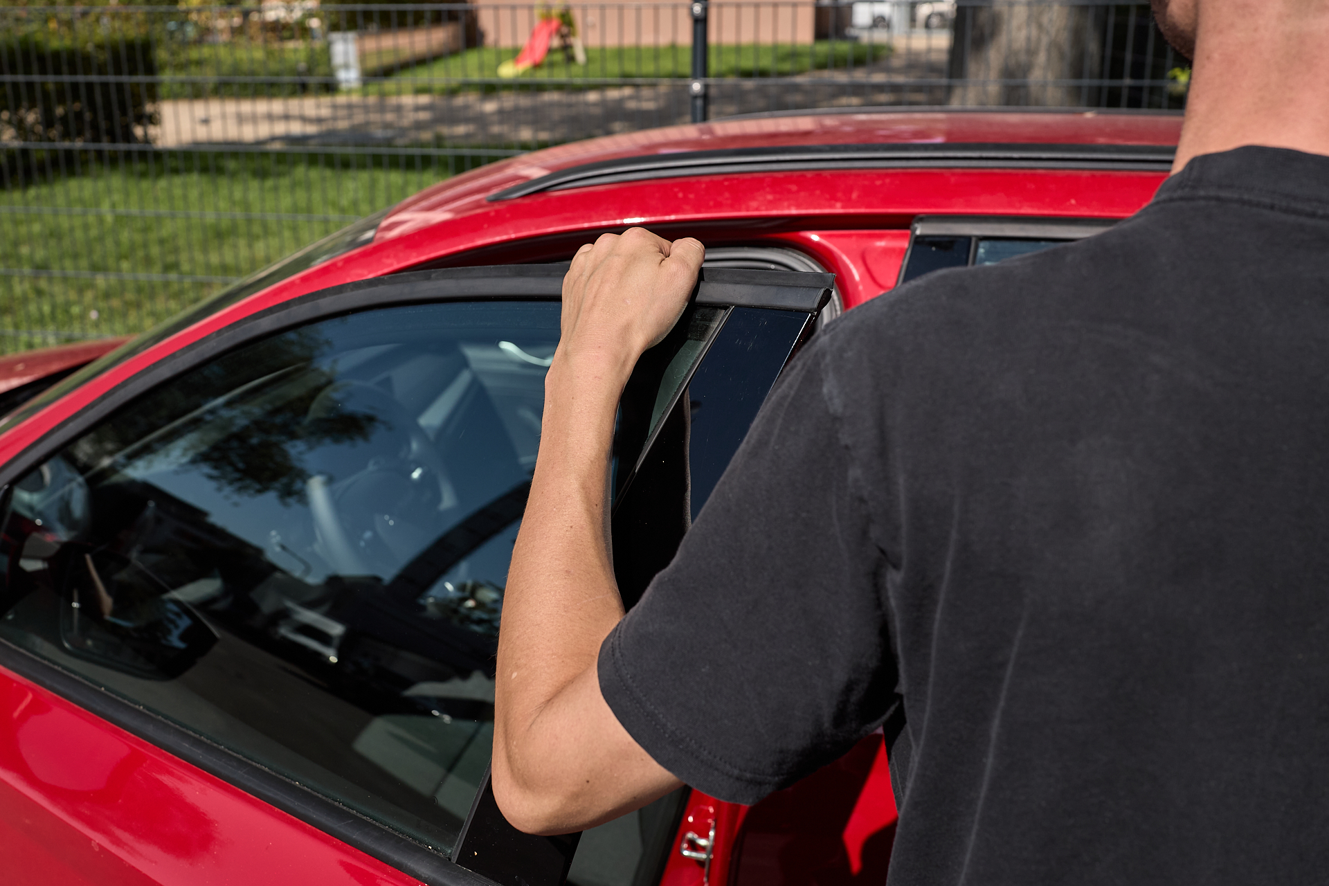 Ein Arm an einer geöffneten Autotür eines roten teilAuto-Fahrzeuges